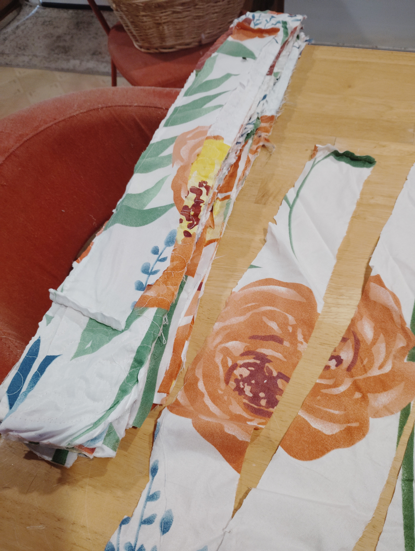 Stacks of floral Soul Cloth strips and longer torn pieces gathered on a kitchen table before stitching